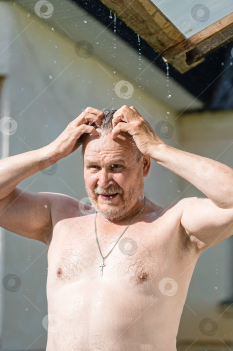 Скачать Мужчина с обнаженной грудью остывает в жару под струями летнего дождя, стекающими с крыши фотосток Ozero