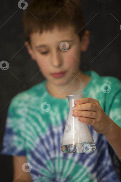 Скачать Мальчик проводит научный химический эксперимент с жидким азотом. Ребенок со стеклянной колбой, наполненной дымом. фотосток Ozero