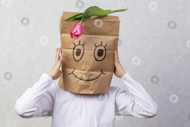 Скачать Ребенок нарисовал улыбку на бумажном пакете и надел его себе на голову. Концепция анонимного подарка. фотосток Ozero