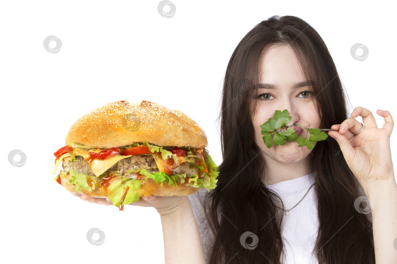 Скачать На заднем плане женщина держит большой бутерброд с гамбургером барбекю. Концепция фаст-фуда. У девушки огромный гамбургер. фотосток Ozero