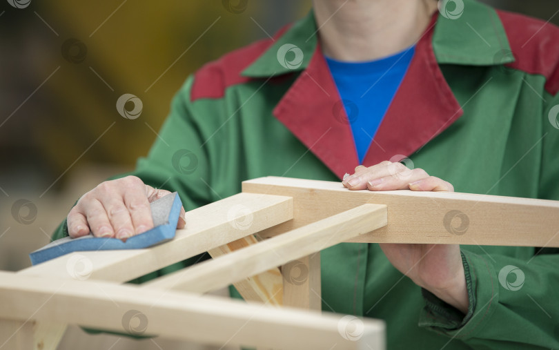 Скачать Руки рабочего деревообрабатывающего завода вытачивают деревянные стулья из натурального дерева. Деревообрабатывающая промышленность. фотосток Ozero