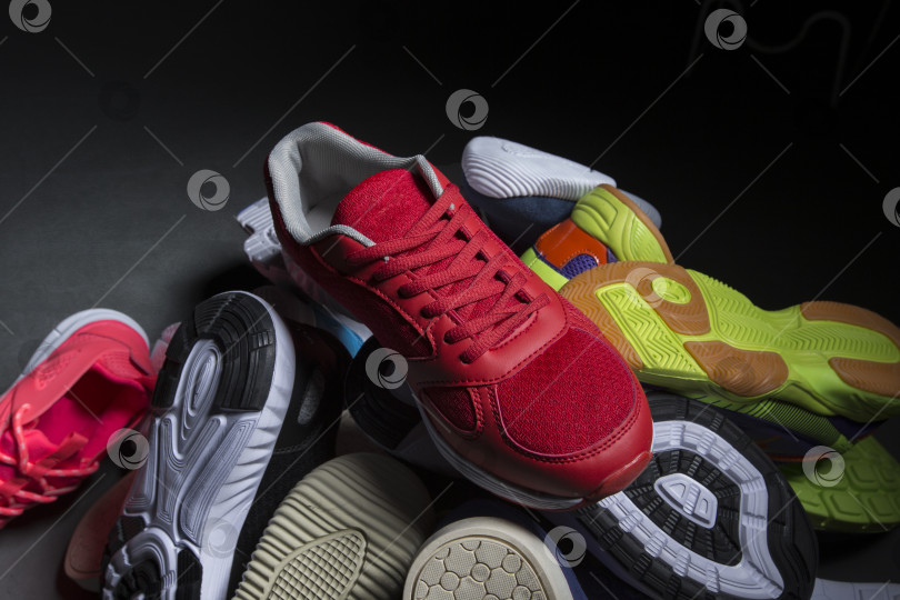 Скачать Разноцветные кроссовки сложены в стопку на сером фоне. Спортивная обувь. фотосток Ozero