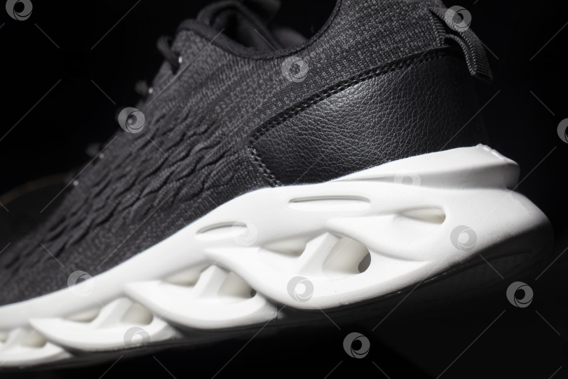 Скачать Черные тканевые кроссовки с белой подошвой на черном фоне. фотосток Ozero