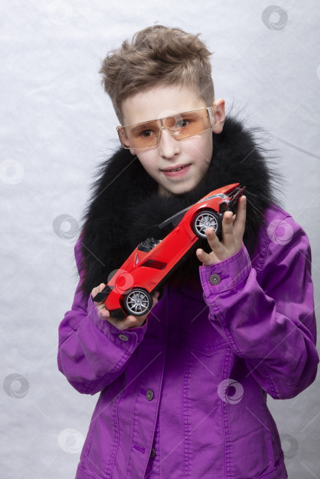 Скачать Модный мальчик держит в руках игрушечную машинку на разноцветном студийном фоне. Красивый ребенок в футуристических очках, мечтающий о дорогой машине. Мечтает о ребенке. Богатый ребенок. фотосток Ozero