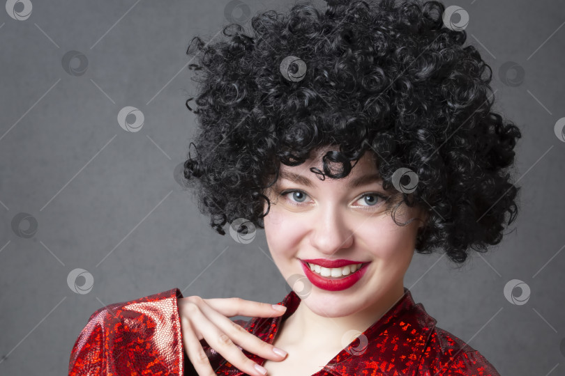 Скачать Возбужденная женщина в африканском парике на сером фоне. Девушка с дискотеки. фотосток Ozero