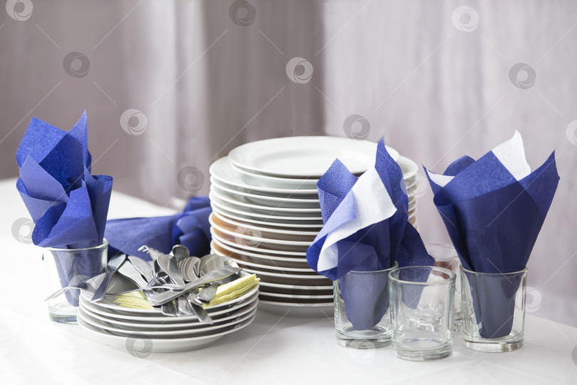 Скачать Стопка пустых тарелок и салфеток в ресторане на столе. фотосток Ozero