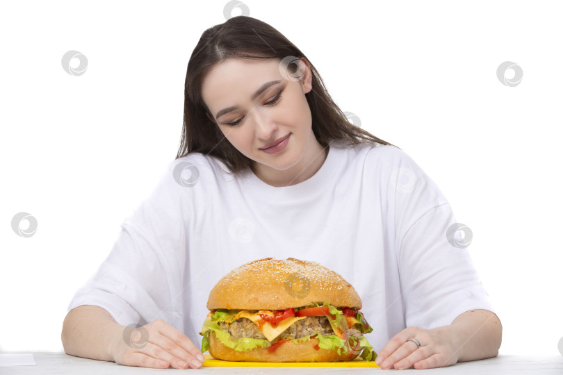 Скачать На заднем плане женщина держит большой бутерброд с гамбургером барбекю. Концепция фаст-фуда. У девушки огромный гамбургер. фотосток Ozero