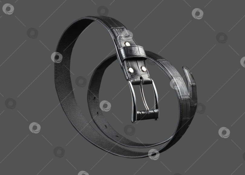 Скачать Черный кожаный ремень, закрученный по спирали на сером фоне. фотосток Ozero