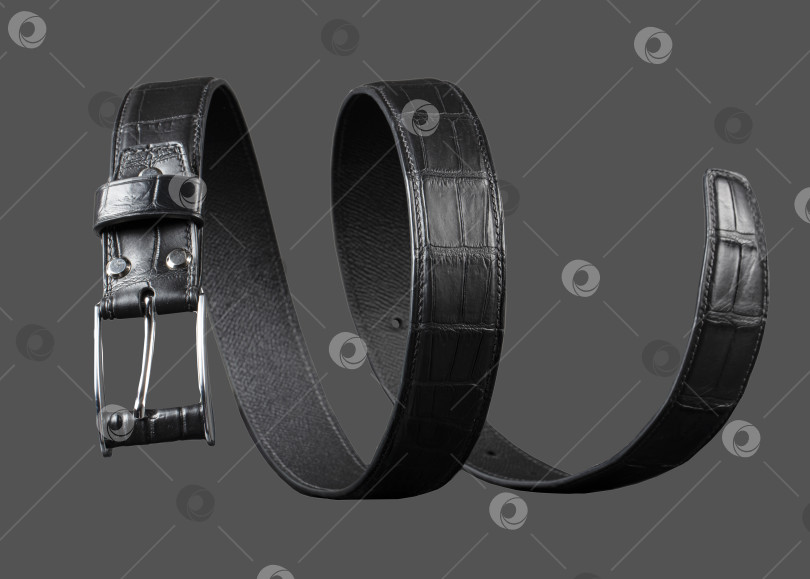 Скачать Черный кожаный ремень, закрученный по спирали на сером фоне. фотосток Ozero