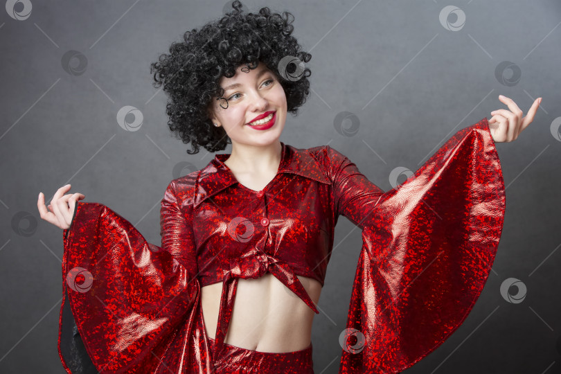 Скачать Забавная винтажная женщина в афро-парике и дискотечном костюме на сером фоне. Девушка в стиле семидесятых. фотосток Ozero