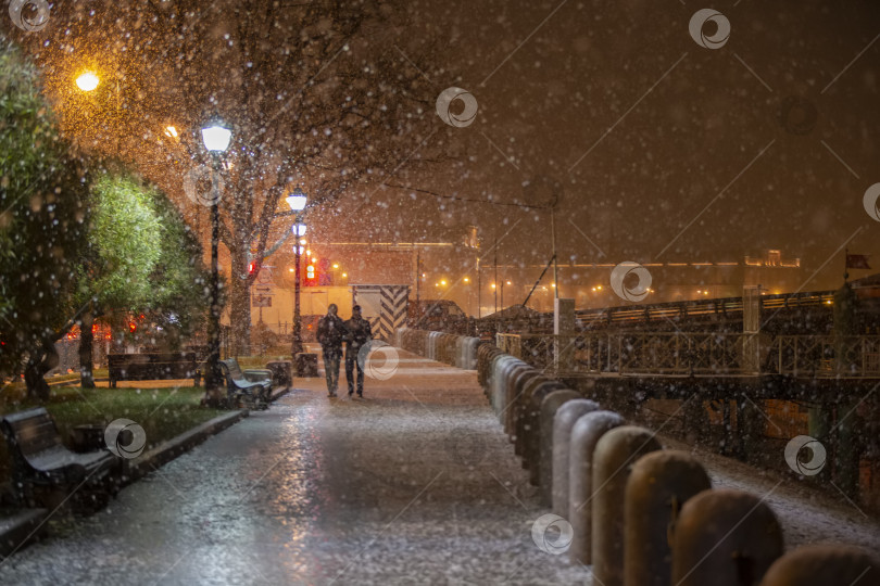 Скачать Заснеженный фон ночного города со случайными прохожими. фотосток Ozero