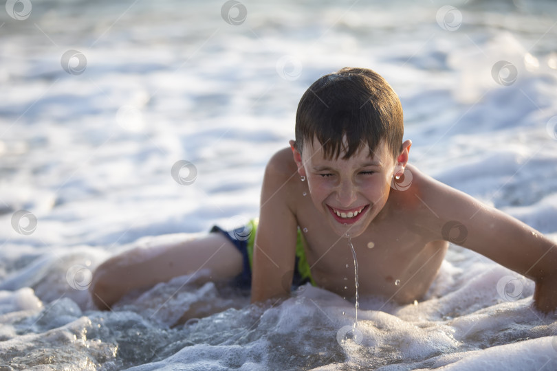 Скачать Счастливый мальчик-подросток играет с морскими волнами. Мальчик плавает в море. фотосток Ozero