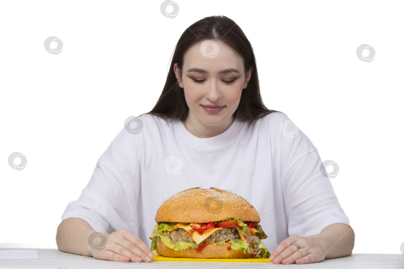 Скачать На заднем плане женщина держит большой бутерброд с гамбургером барбекю. Концепция фаст-фуда. У девушки огромный гамбургер. фотосток Ozero