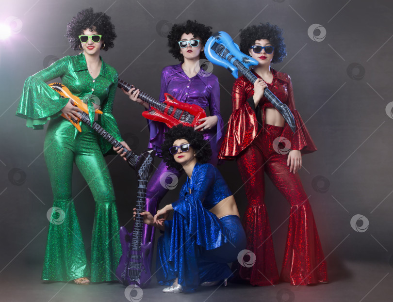 Скачать Девушки в ярких блестящих костюмах и париках с гитарами. Диско-группа с винтажной музыкой для женщин в стиле диско. фотосток Ozero