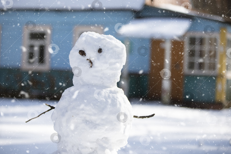 Скачать Забавный снеговик с ветками вместо рук и глаз на фоне летящих снежинок. фотосток Ozero