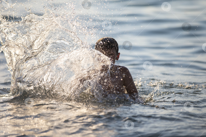 Скачать Счастливый мальчик-подросток играет с морскими волнами. Мальчик плавает в море. фотосток Ozero