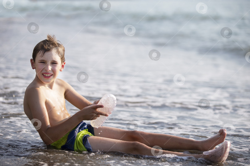 Скачать Мальчик-подросток сидит на берегу моря. фотосток Ozero