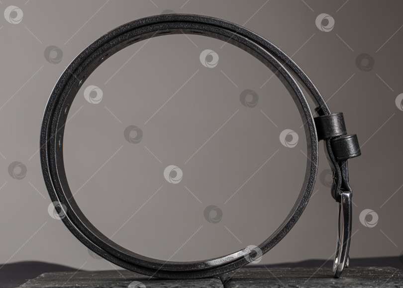 Скачать Кожаный ремень, скрученный в круг на сером фоне. фотосток Ozero