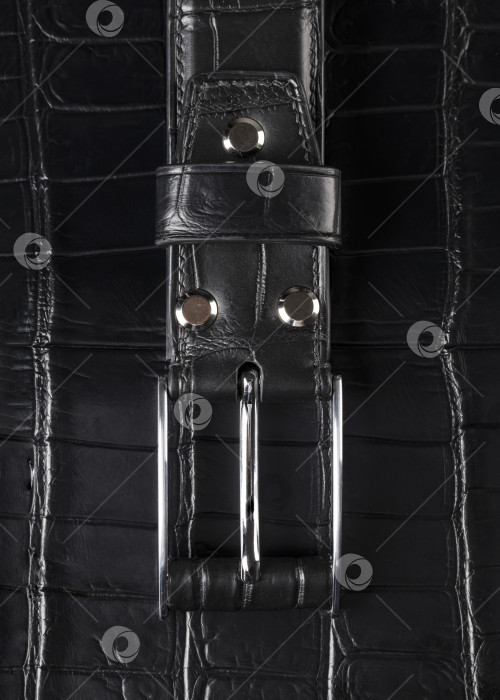 Скачать Черный кожаный ремень с металлической бляхой крупным планом на сером фоне. фотосток Ozero