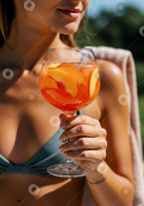 Скачать Белая женщина с освежающим летним персиковым напитком в руках. Фруктовый коктейль для отдыха у бассейна. фотосток Ozero