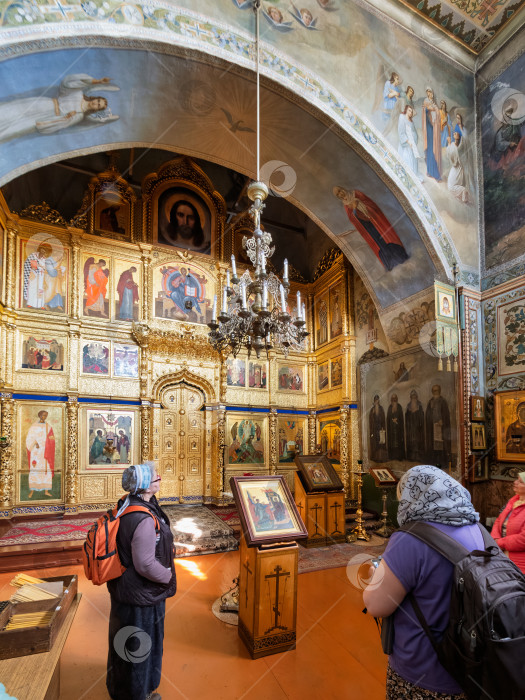 Скачать Паломники в Троицком соборе Соловецкого монастыря, рассматривающие богатый старинный интерьер, золоченый иконостас и старинные фрески фотосток Ozero