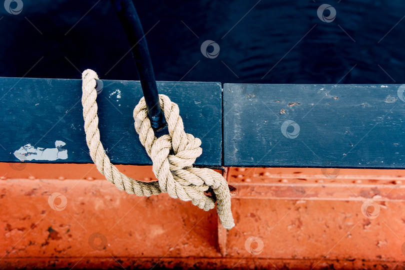 Скачать Крупный план швартовного троса с завязанным узлом концом, обвязанного вокруг планки на оборудовании пирса фотосток Ozero