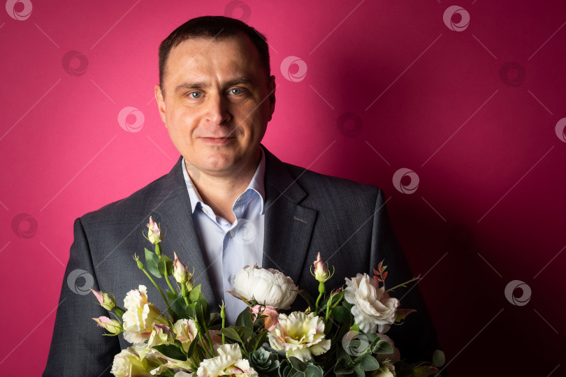 Скачать красивый бизнесмен в костюме смотрит в камеру с букетом цветов. фотосток Ozero