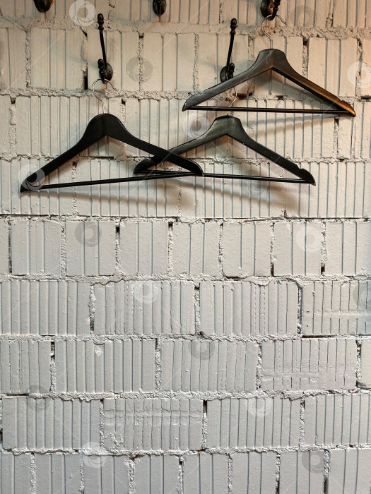 Скачать Пустые вешалки на фоне текстурированной кирпичной стены с пространством для копирования модной или розничной концепции фотосток Ozero