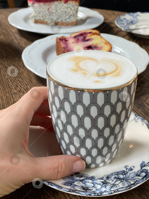 Скачать Капучино в элегантной кружке на узорчатой тарелке с кусочками торта на заднем плане, уютная атмосфера фотосток Ozero