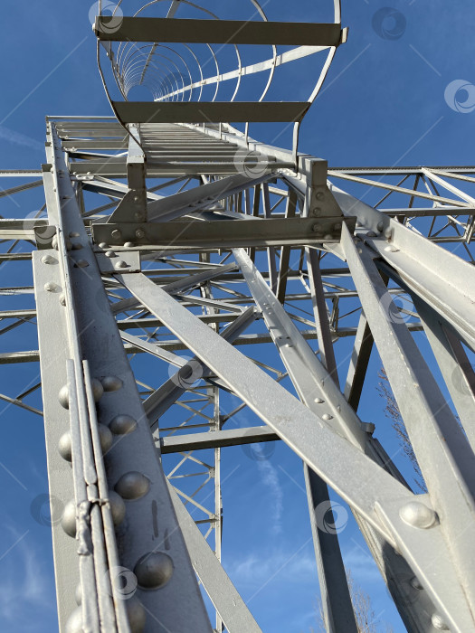 Скачать Смотрю вверх на металлическую передающую башню на фоне голубого неба с геометрическими узорами фотосток Ozero
