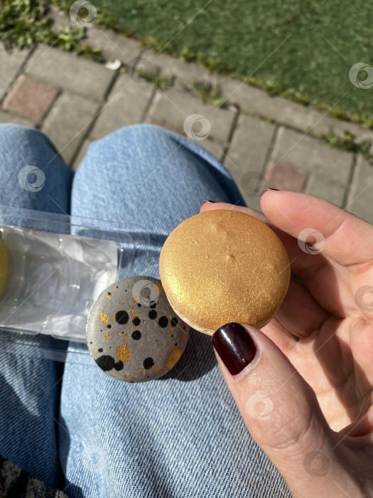 Скачать Два раскрашенных камня в руке на открытом воздухе при солнечном свете, один золотой, другой серый с черными точками фотосток Ozero