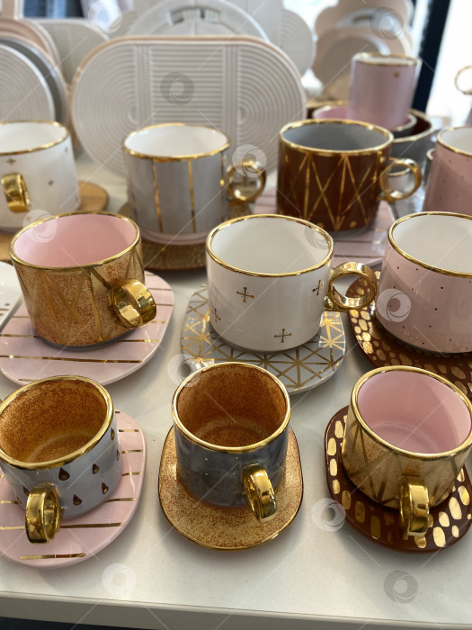 Скачать На столе были выставлены различные керамические кофейные чашки и блюдца розового и золотого цветов фотосток Ozero