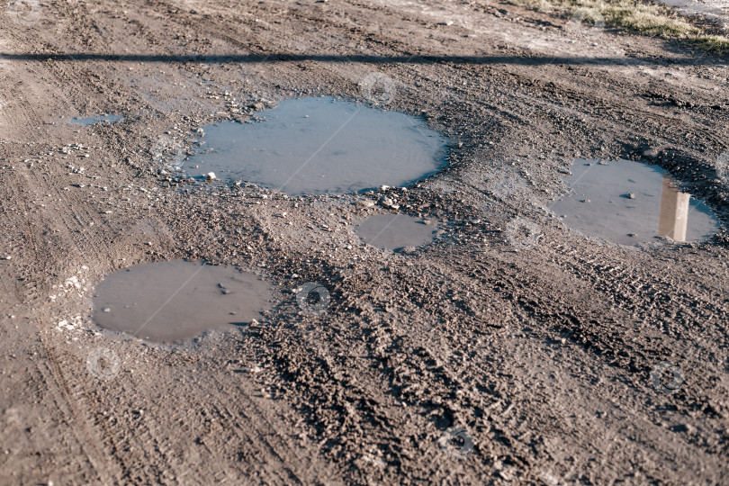 Скачать Крупный план грунтовой дороги с несколькими лужами воды, демонстрирующий текстуру грунта и отражения. фотосток Ozero