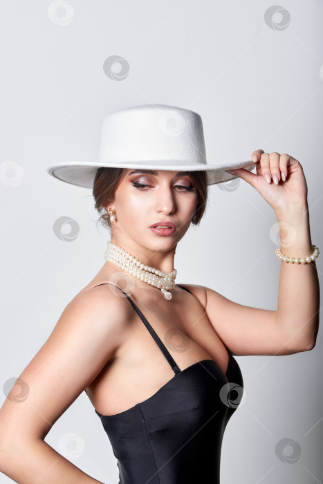 Скачать Женщина в черном платье и белой шляпе в студии фотосток Ozero