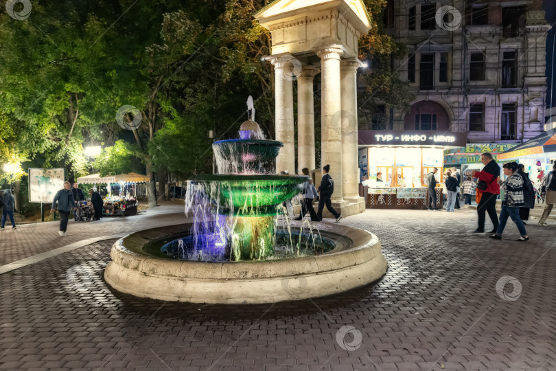 Скачать Небольшой фонтан с вечерней подсветкой у входа в курортный парк фотосток Ozero