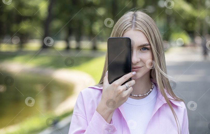Скачать Молодая блондинка показывает экран смартфона фотосток Ozero