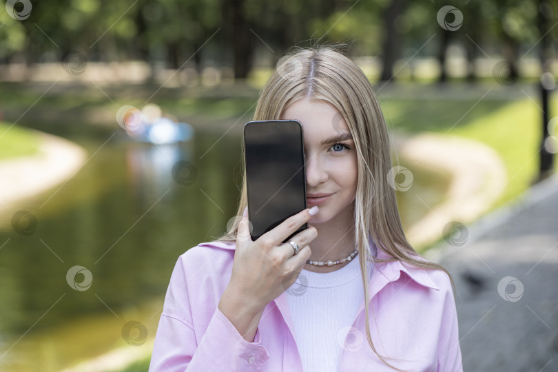 Скачать Молодая блондинка показывает экран смартфона фотосток Ozero
