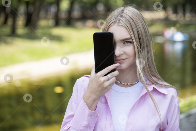Скачать Молодая блондинка показывает экран смартфона фотосток Ozero