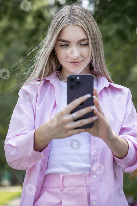 Скачать Молодая красивая девушка читает сообщение на смартфоне фотосток Ozero