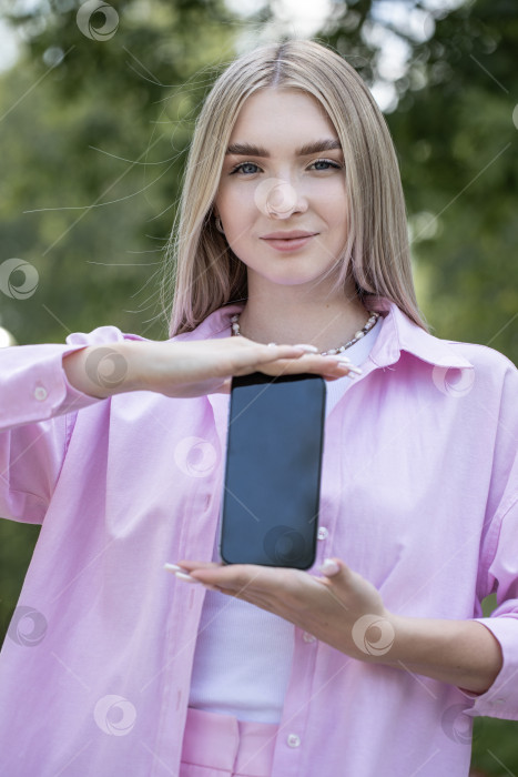 Скачать Молодая блондинка показывает экран смартфона фотосток Ozero