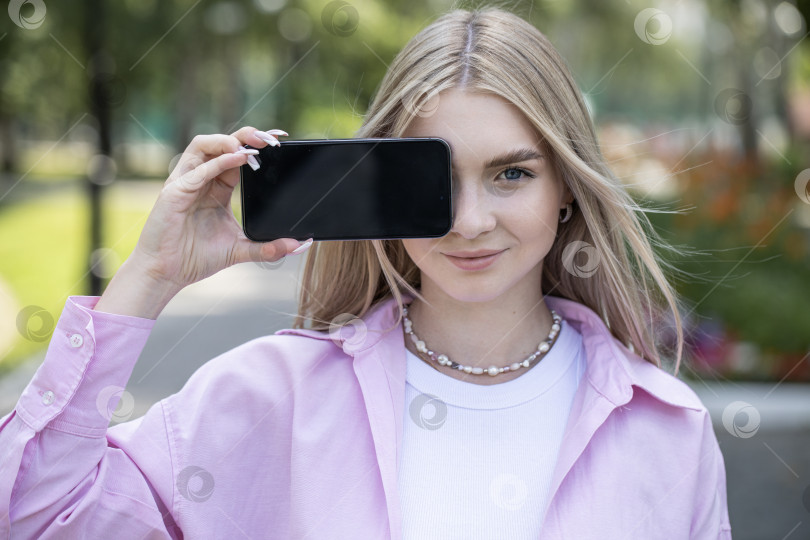 Скачать Молодая блондинка показывает экран смартфона фотосток Ozero
