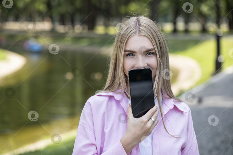 Скачать Молодая блондинка показывает экран смартфона фотосток Ozero