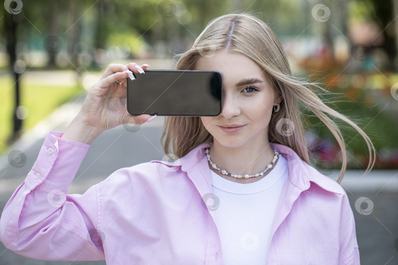 Скачать Молодая блондинка показывает экран смартфона фотосток Ozero
