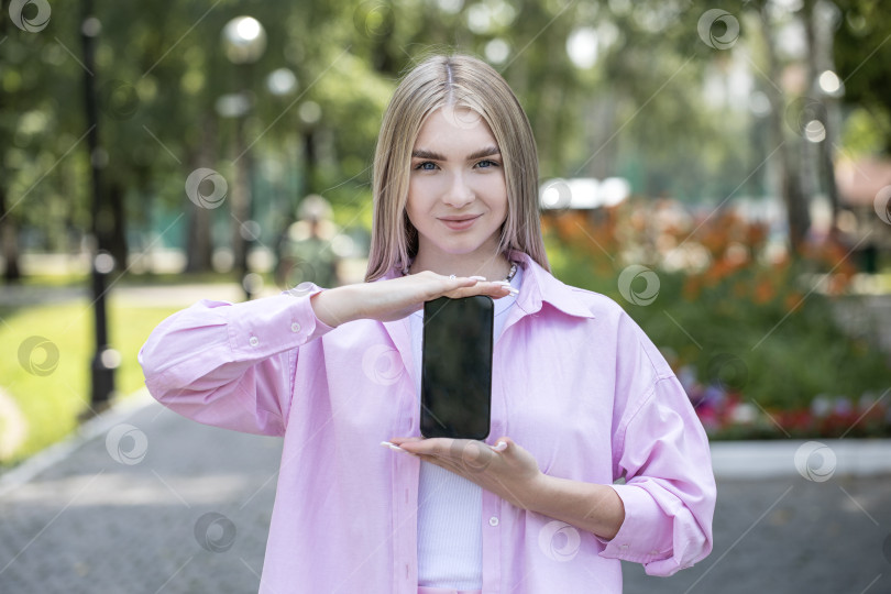 Скачать Молодая блондинка показывает экран смартфона фотосток Ozero