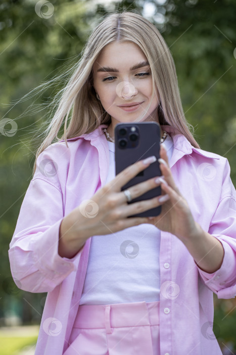 Скачать Молодая красивая девушка читает сообщение на смартфоне фотосток Ozero