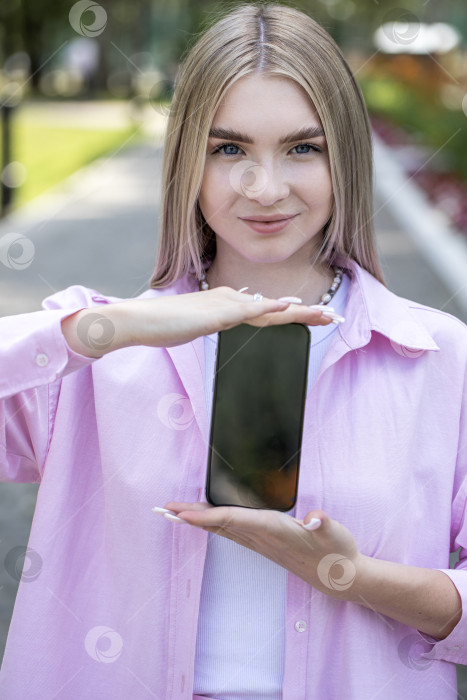 Скачать Молодая блондинка показывает экран смартфона фотосток Ozero
