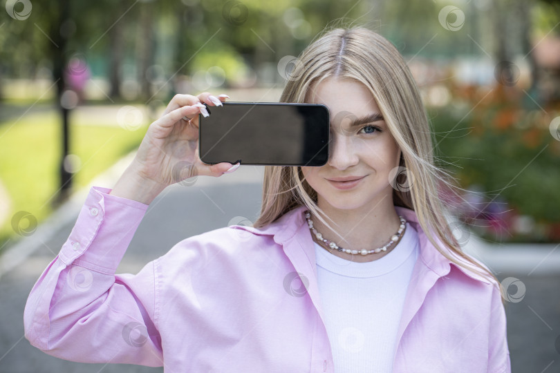 Скачать Молодая блондинка показывает экран смартфона фотосток Ozero