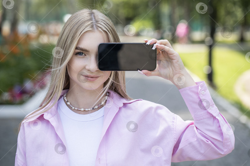 Скачать Молодая блондинка показывает экран смартфона фотосток Ozero