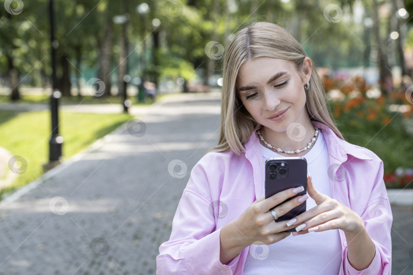 Скачать Молодая красивая девушка читает сообщение на смартфоне фотосток Ozero
