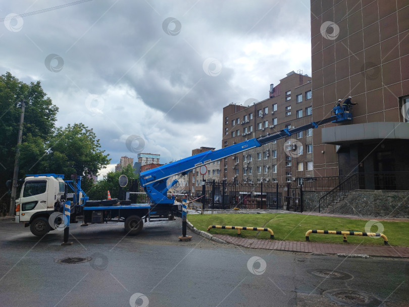Скачать Ремонт фасада здания на высоте при помощи автомобильной вышки. Реконструкция фасада здания на высоте с использованием автовышки. фотосток Ozero